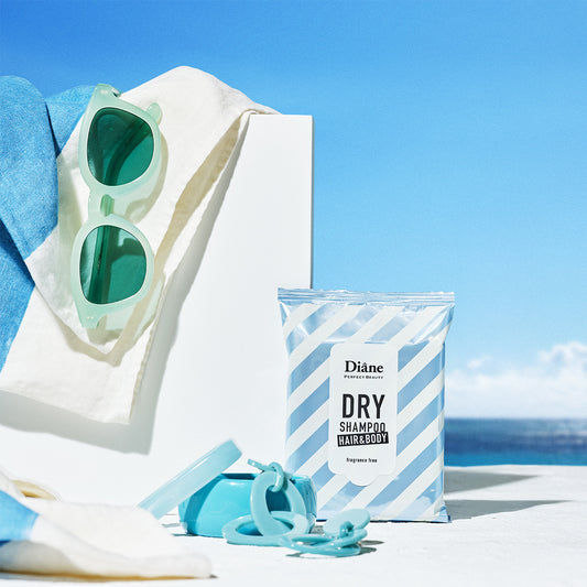 Sunglasses, towel, and Diane dry shampoo wipe on a beach with ocean view