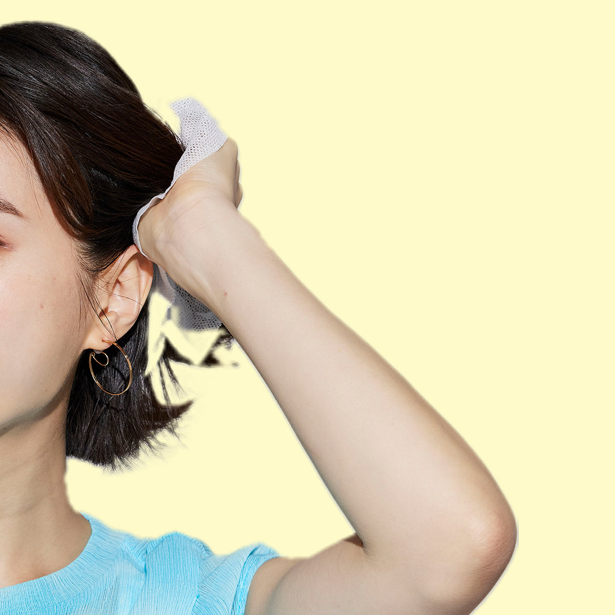 Woman with a mesh cloth wipe on her hand to wrap hair against a yellow background