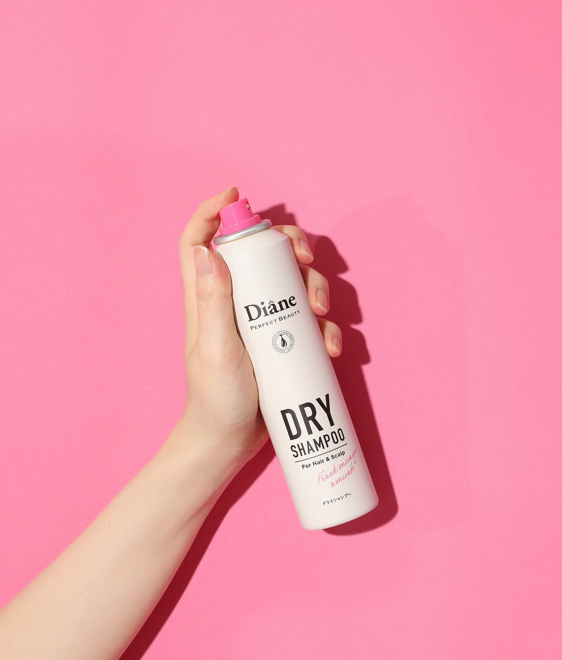 holding Perfect Beauty Dry Shampoo Fresh Mango & Fruit on a pink background